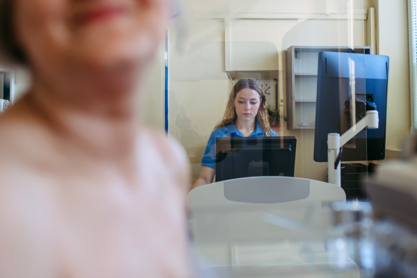 Healthcare worker performing mammography on older woman