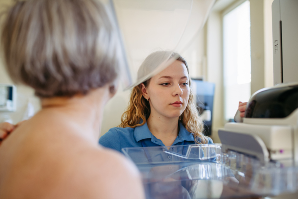 Healthcare worker performing mammography on older woman