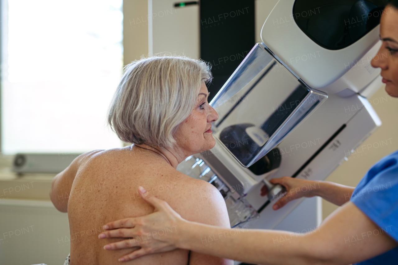 Radiology nurse helping senior woman with mammogram