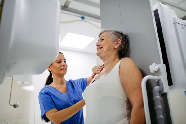 Senior woman positioned on radiographic wall stand for diagnostic imaging