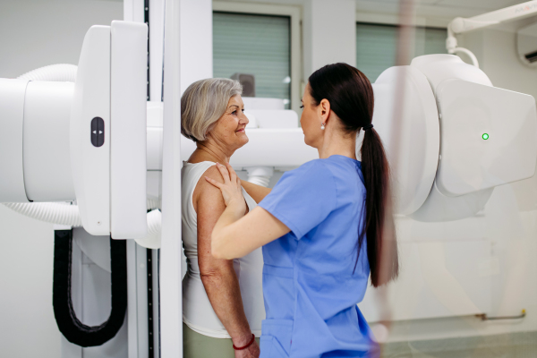 Senior woman positioned on radiographic wall stand for diagnostic imaging