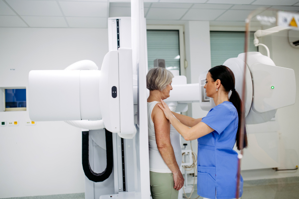 Senior woman positioned on radiographic wall stand for diagnostic imaging