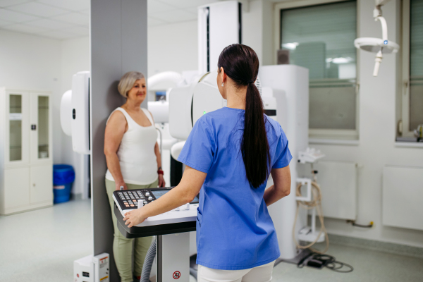 Senior woman positioned on radiographic wall stand for diagnostic imaging