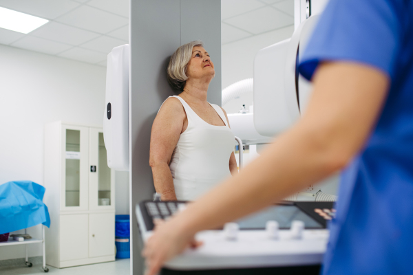 Senior woman positioned on radiographic wall stand for diagnostic imaging