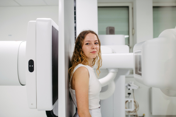 Woman positioned upright against wall stand for radiographic examination