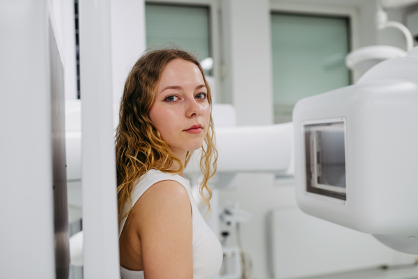 Woman positioned upright against wall stand for radiographic examination