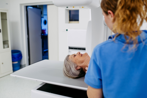 Nurse positioning elderly patient on tilting fluoroscopy table for X-ray scan