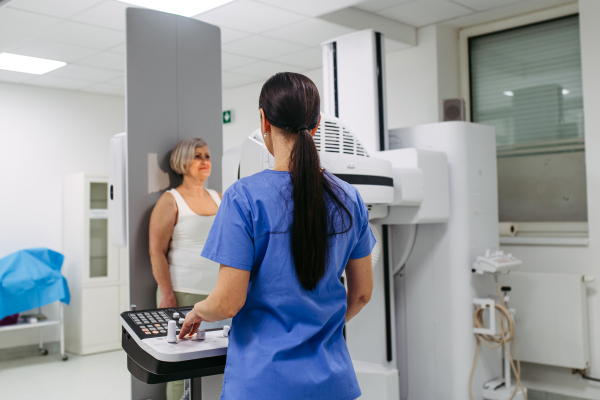 Senior woman positioned on radiographic wall stand for diagnostic imaging