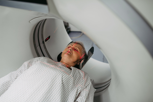 Senior patient positioned for head scan with laser alignment in CT scanner