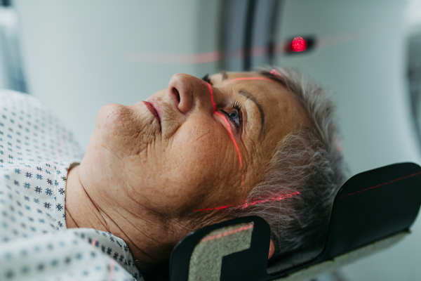 Senior patient positioned for head scan with laser alignment in CT scanner