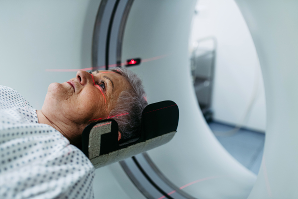 Senior undergoing head scan with laser guidance in CT machine