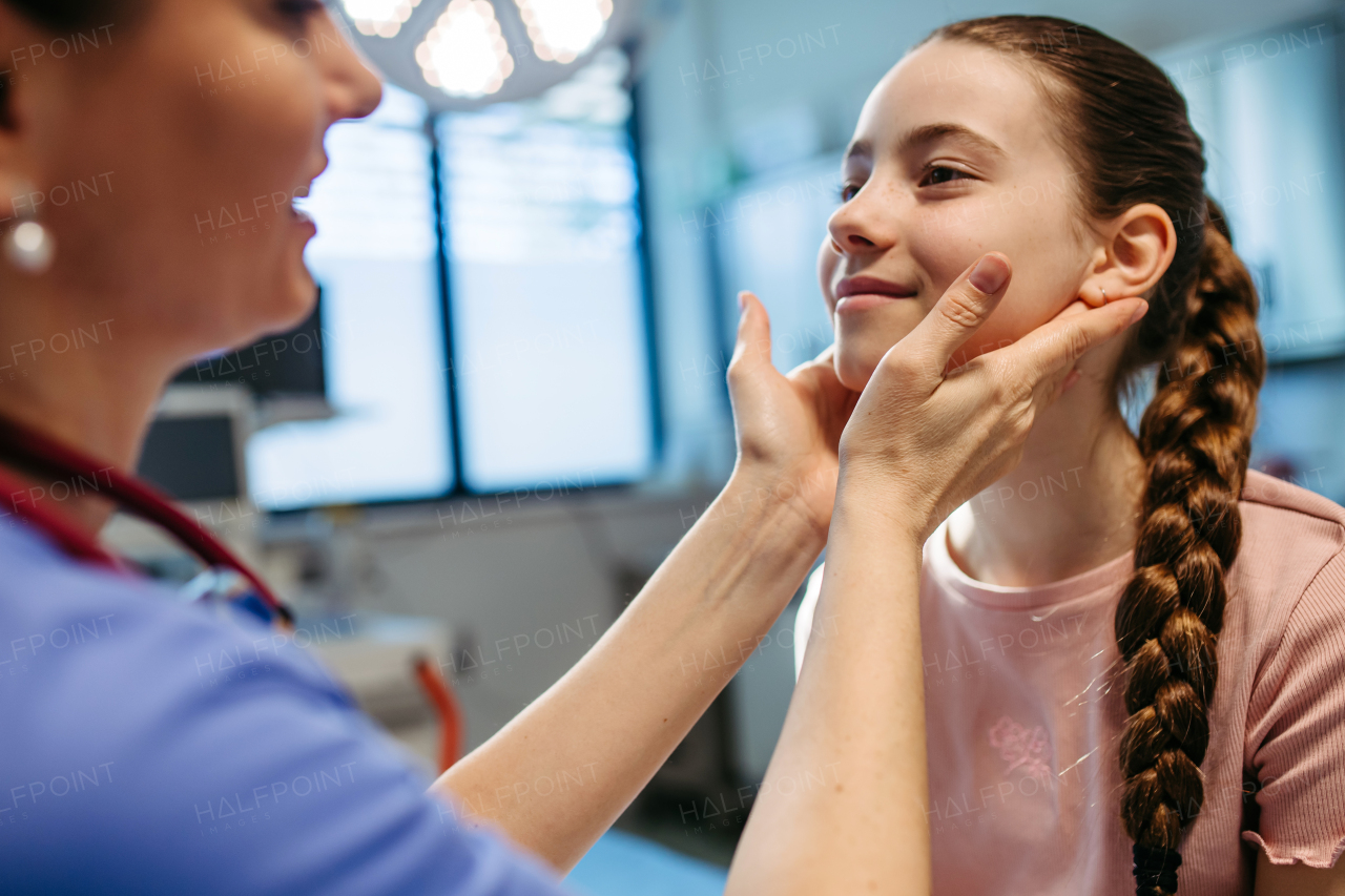 Doctor examining girl's neck for swollen lymph nodes.
