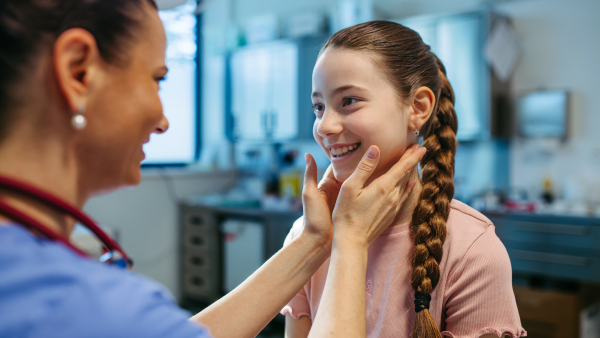 Pediatrician palpating lymph nodes during routine health check.