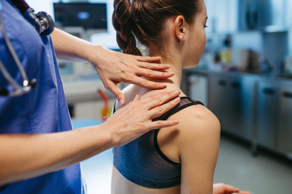Doctor evaluating child's spine for scoliosis during check-up.