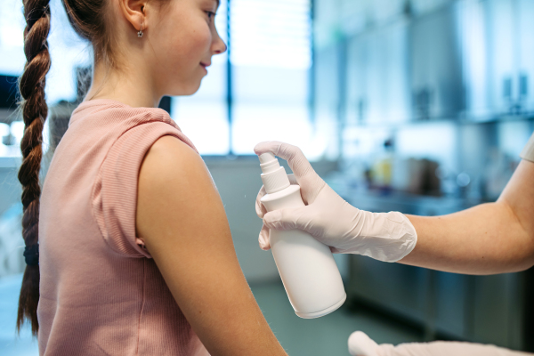 Nurse cleans the girl's skin with antiseptic in preparation for vaccination.