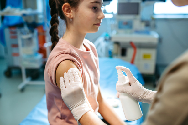 Nurse cleans the girl's skin with antiseptic in preparation for vaccination.