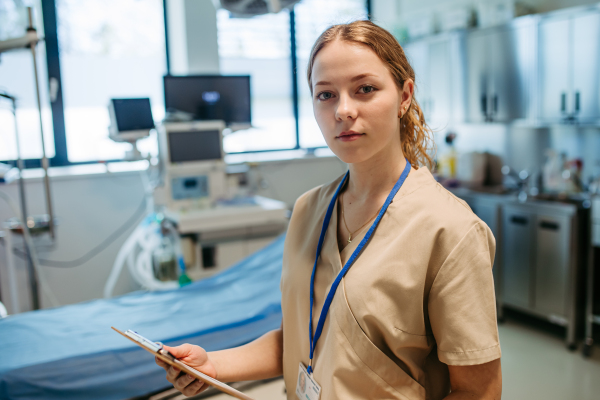Confident young nurse holding patient chart in hospital room.