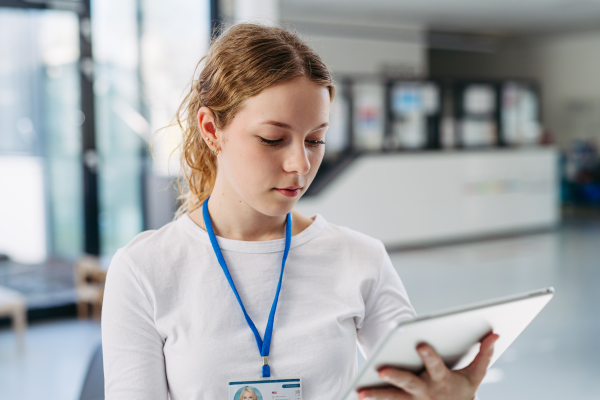 Portrait of female doctor standing in hospital hallway, reading document in tablet.