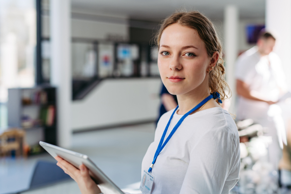 Portrait of female doctor standing in hospital hallway, holding tablet,
