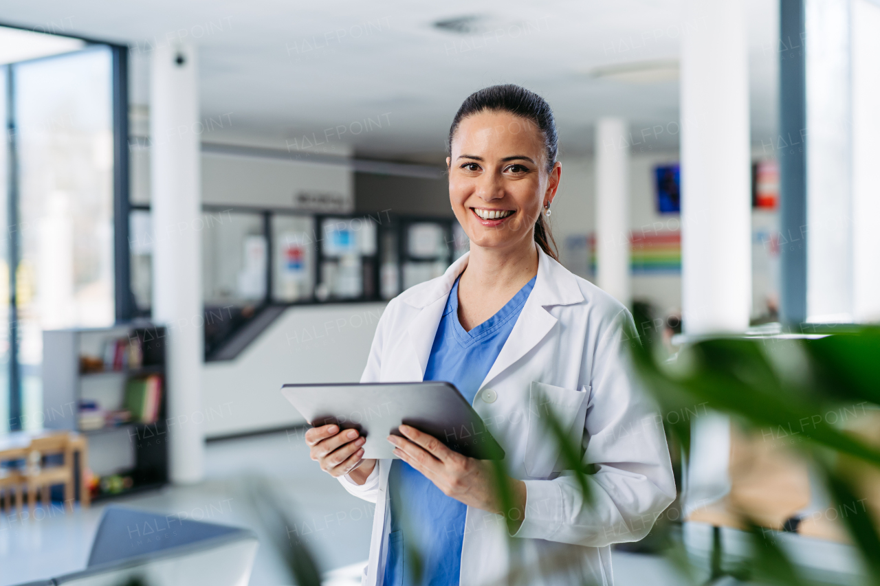 Portrait of female doctor standing in hospital hallway and making phone call.