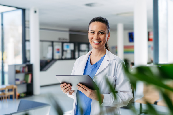Portrait of female doctor standing in hospital hallway and making phone call.