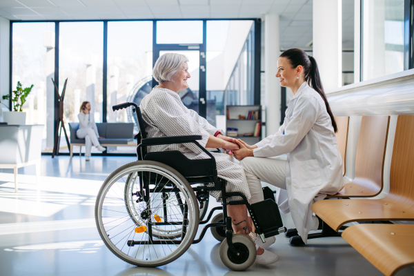 Caring physician speaking with senior patient in wheelchair. Senior health care.