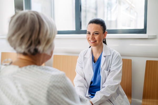 Caring physician speaking with senior patient in wheelchair. Senior health care.
