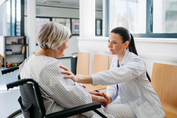 Caring physician speaking with senior patient in wheelchair. Senior health care.