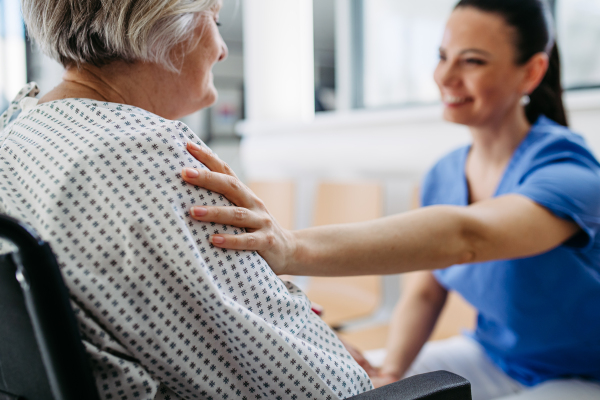 Compassionate healthcare worker interacting with elderly patient in wheelchair