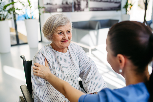 Caring physician speaking with senior patient in wheelchair. Senior health care.