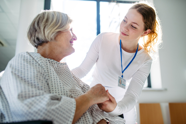 Compassionate healthcare worker interacting with elderly patient in wheelchair