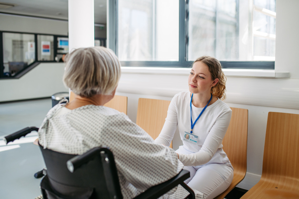 Compassionate healthcare worker interacting with elderly patient in wheelchair