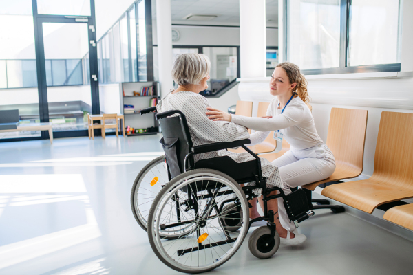Caring physician speaking with senior patient in wheelchair. Senior health care.