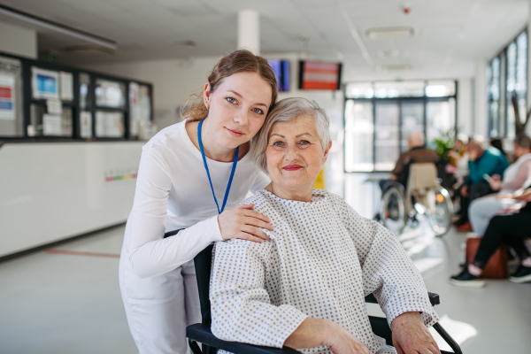 Elderly patient in wheelchair and female physician smiling. Senior health care.