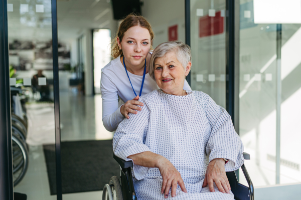 Elderly patient in wheelchair and female physician smiling. Senior health care.
