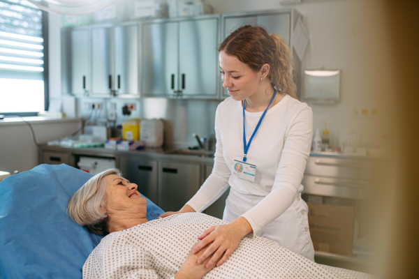 Nurse comforting elderly patient in hospital bed