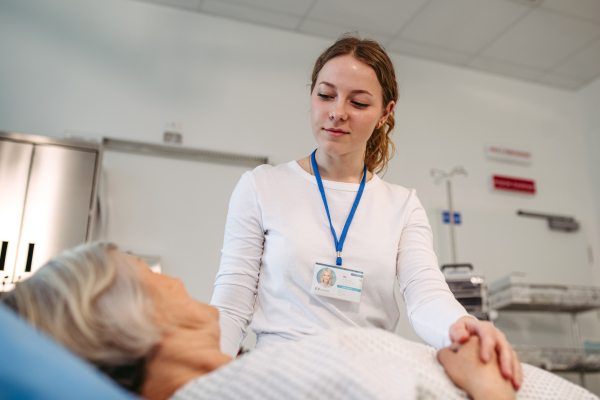 Nurse comforting elderly patient in hospital bed