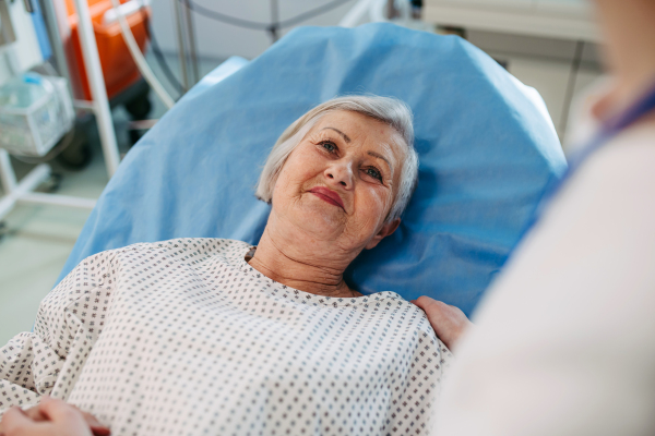 Nurse comforting elderly patient in hospital bed