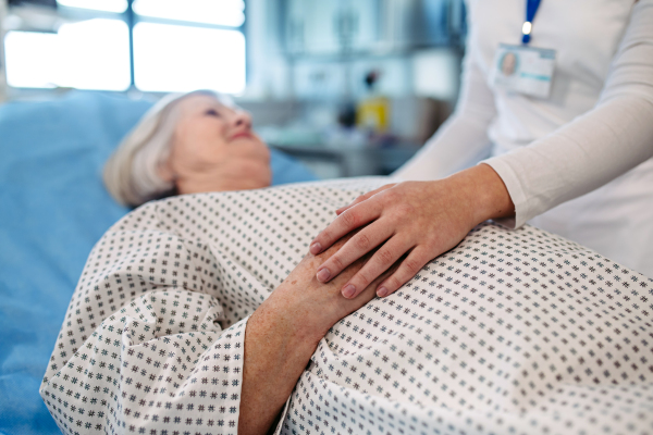 Nurse comforting elderly patient in hospital bed