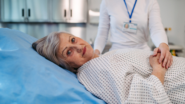 Scared elderly patient lying in hospital bed