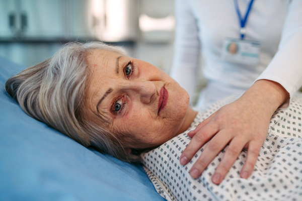 Scared elderly patient lying in hospital bed