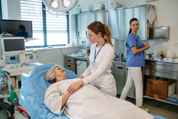 Nurse comforting elderly patient in hospital bed