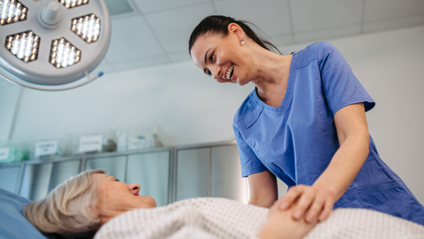Nurse comforting elderly patient in hospital bed