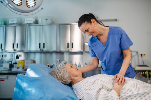 Nurse comforting elderly patient in hospital bed