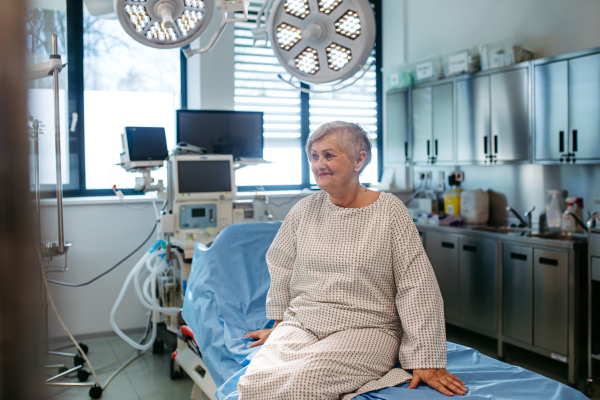 Senior patient in medical gown waiting for for procedure in hospital.