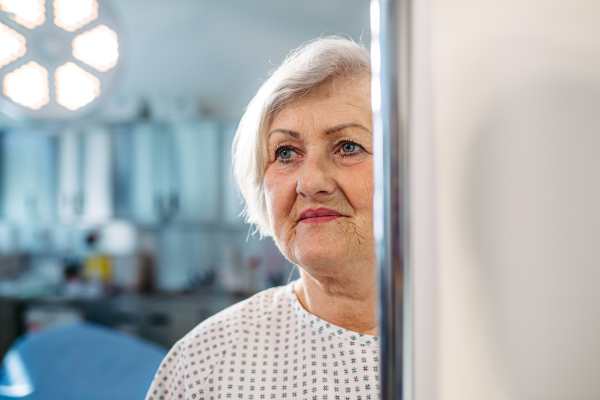 Senior patient in medical gown waiting for for procedure in hospital.