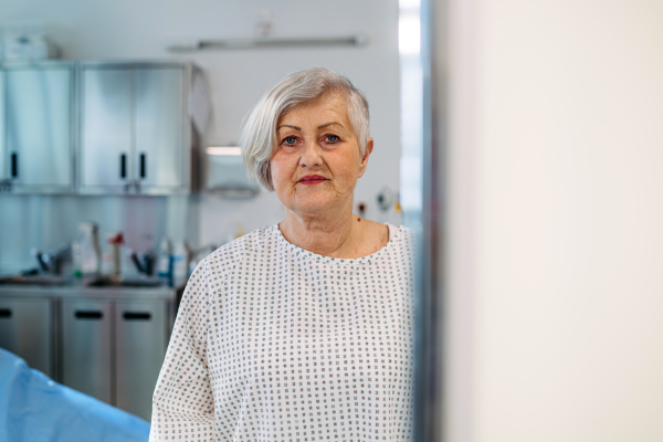 Senior patient in medical gown waiting for for procedure in hospital.