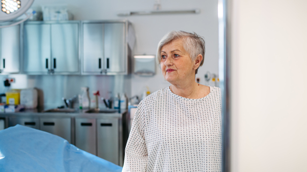 Senior patient in medical gown waiting for for procedure in hospital.