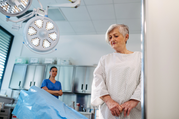 Senior patient in medical gown waiting for for procedure in hospital.