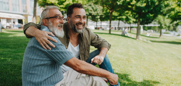 Handsome mature man hugging his older father in park. Fathers day concept.